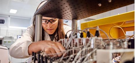 Scientist or technician works on a series of tubes and wires in a lab.