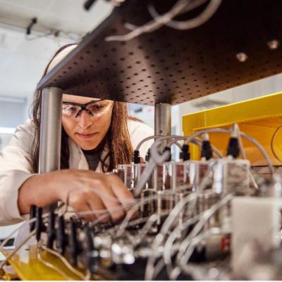 Scientist or technician works on a series of tubes and wires in a lab.