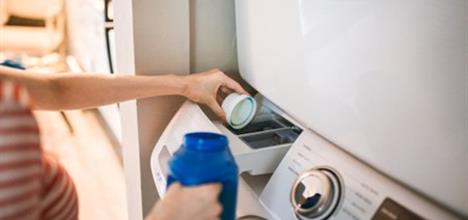 Close up of laundry detergent being put into washing machine. 