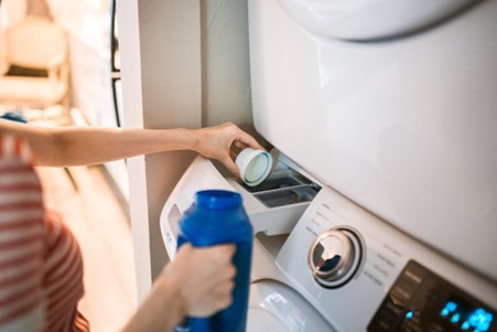 Close up of laundry detergent being put into washing machine. 