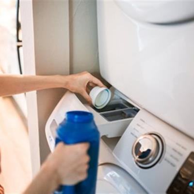 Close up of laundry detergent being put into washing machine. 