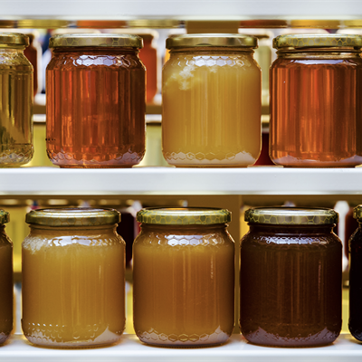 2 lines of jars of honey, all with different colours and consistancies 