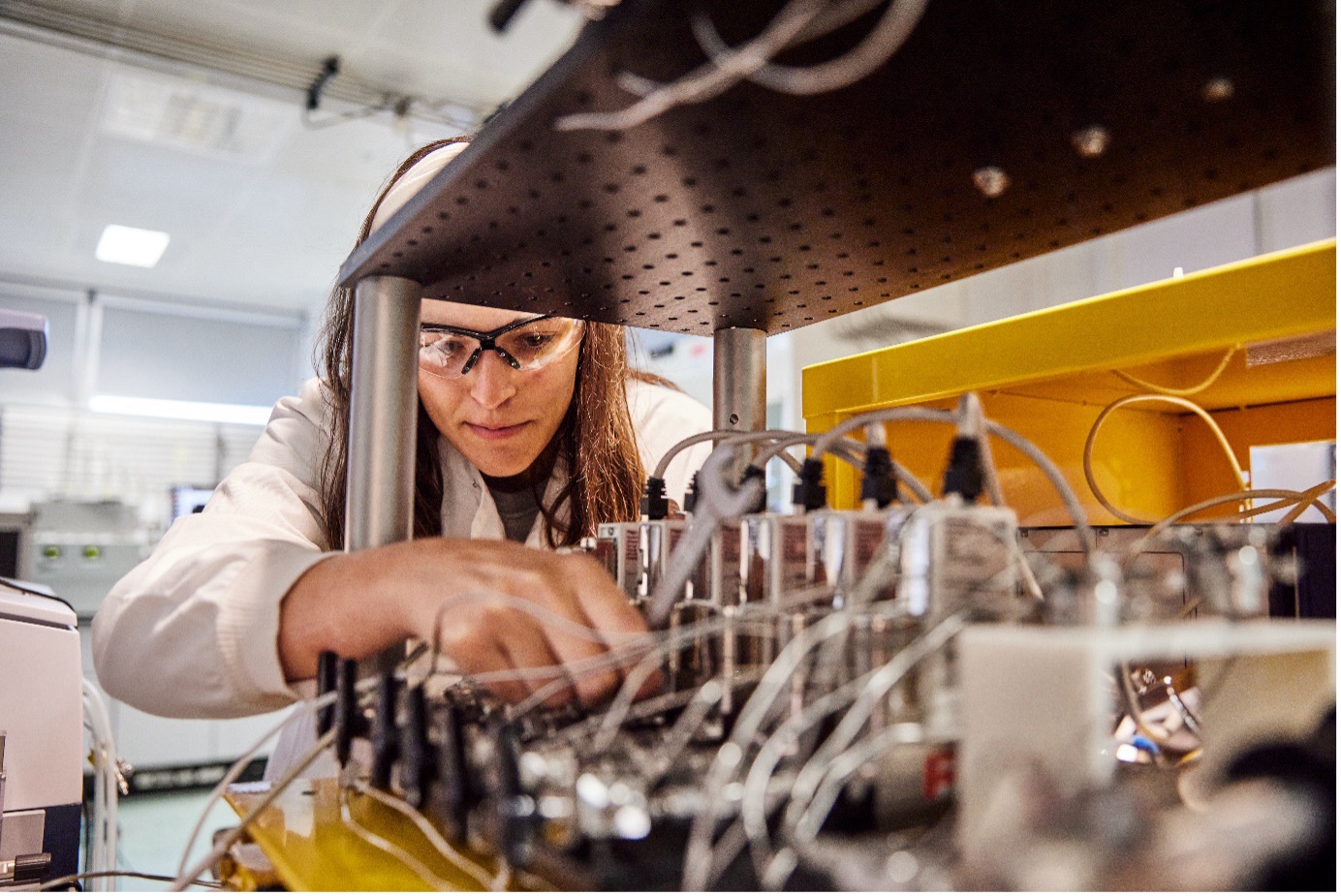 Scientist or technician works on a series of wires and tubes in a lab.